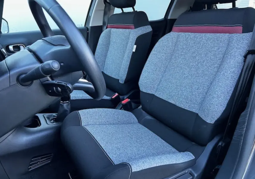 Intérieur avant de la Citroën C3 gris foncé, vue côté conducteur sur les sièges tissu gris et noir avec bande rouge.