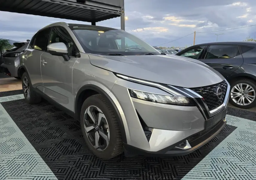 Nissan Qashqai III gris silver en 3/4 avant droit, avec calandre noire et jantes alliage 18 pouces visibles.