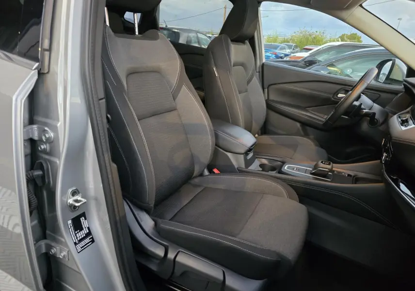 Vue intérieure côté conducteur du Nissan Qashqai gris silver 2024, mettant en valeur les sièges noirs et la console centrale moderne.