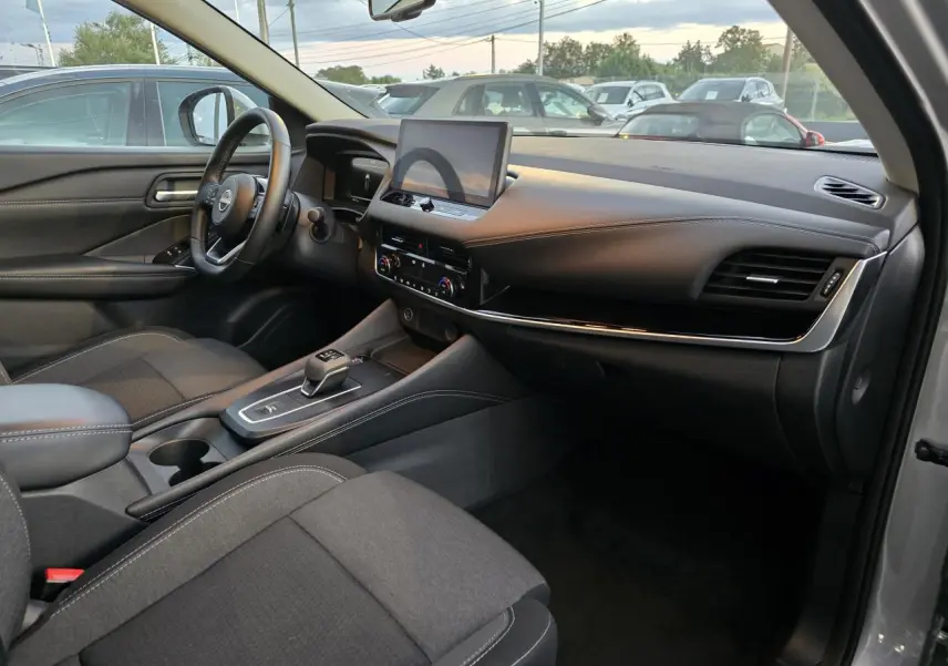 Intérieur du Nissan Qashqai 2024 gris silver, vue côté passager montrant tableau de bord et console centrale moderne.