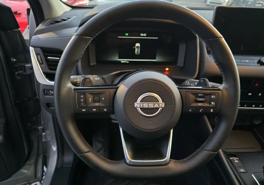 Vue centrée sur le volant cuir du Nissan Qashqai gris silver 2024, avec commandes intégrées et tableau de bord numérique.