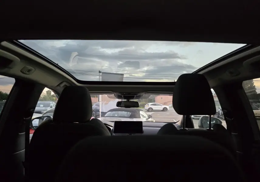 Vue intérieure arrière du Nissan Qashqai gris silver 2024 avec toit panoramique et sièges avant noirs.