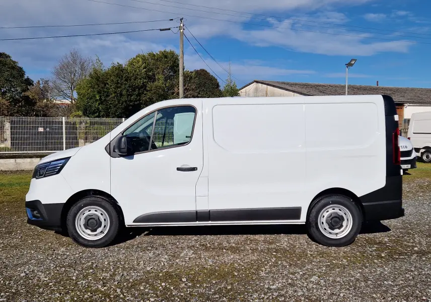 Vue de profil côté gauche du fourgon blanc Renault Trafic L1H1 2025 avec détails noirs sur pare-chocs et bas de caisse.