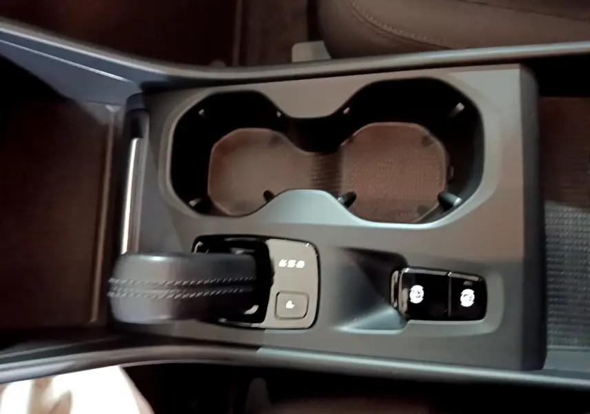 Gros plan sur la console centrale noire du Volvo XC40 Recharge T4 avec levier de vitesse et boutons de contrôle.