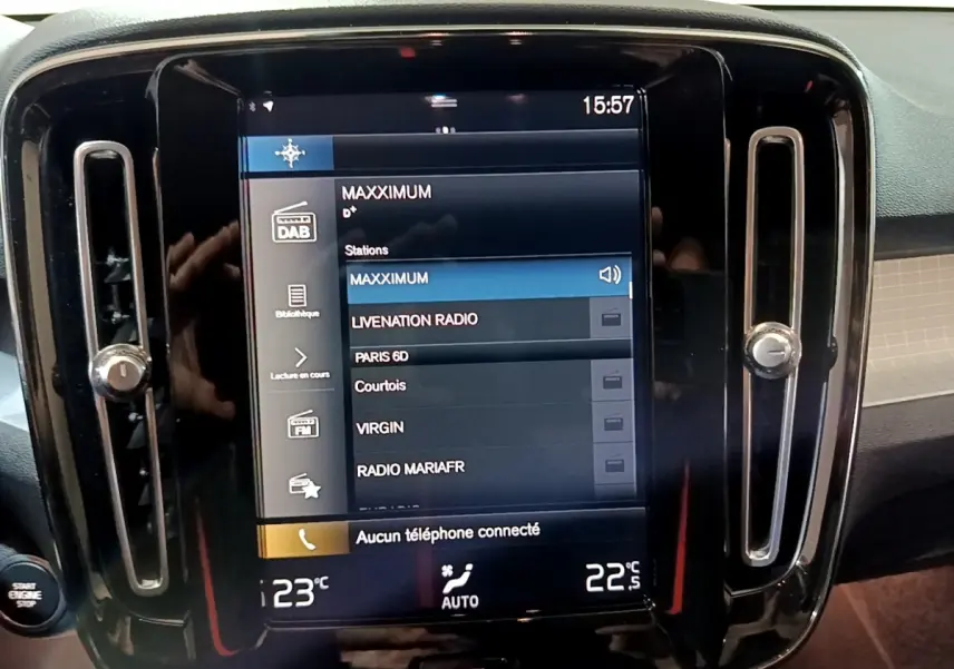 Écran tactile central allumé affichant stations radio, entouré de sorties d'air verticales noires dans Volvo XC40 noir.