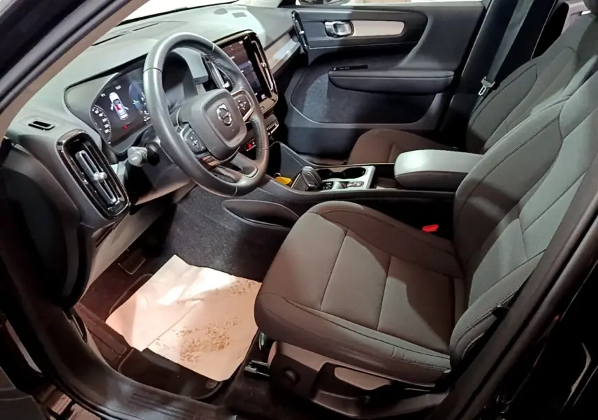 Intérieur avant droit du Volvo XC40 noir 2020, avec tableau de bord numérique et sièges tissu gris foncé.