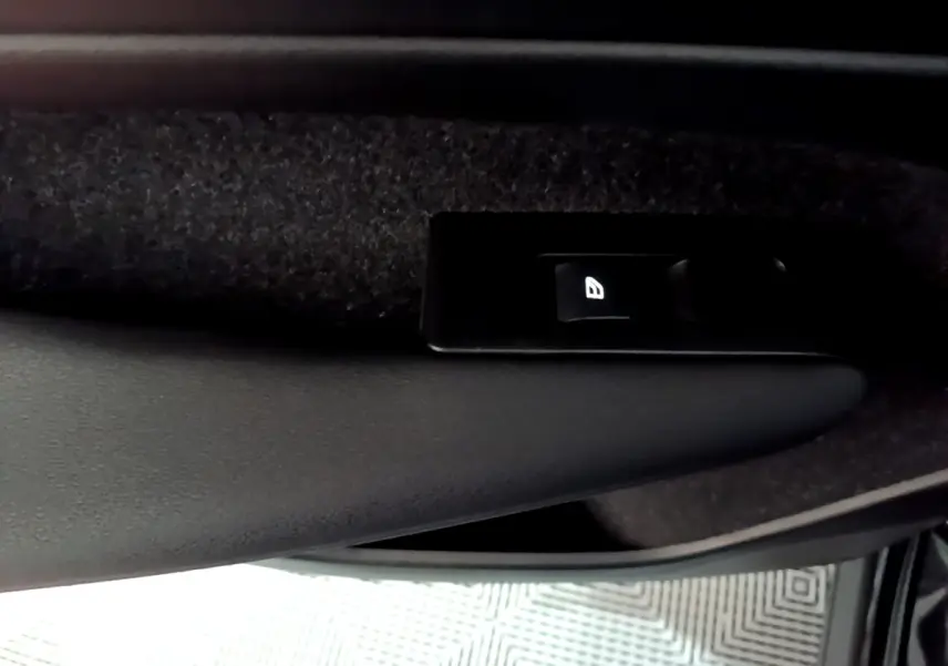 Gros plan sur le bouton de commande de la vitre côté conducteur d'un Volvo XC40 noir, intérieur sombre.