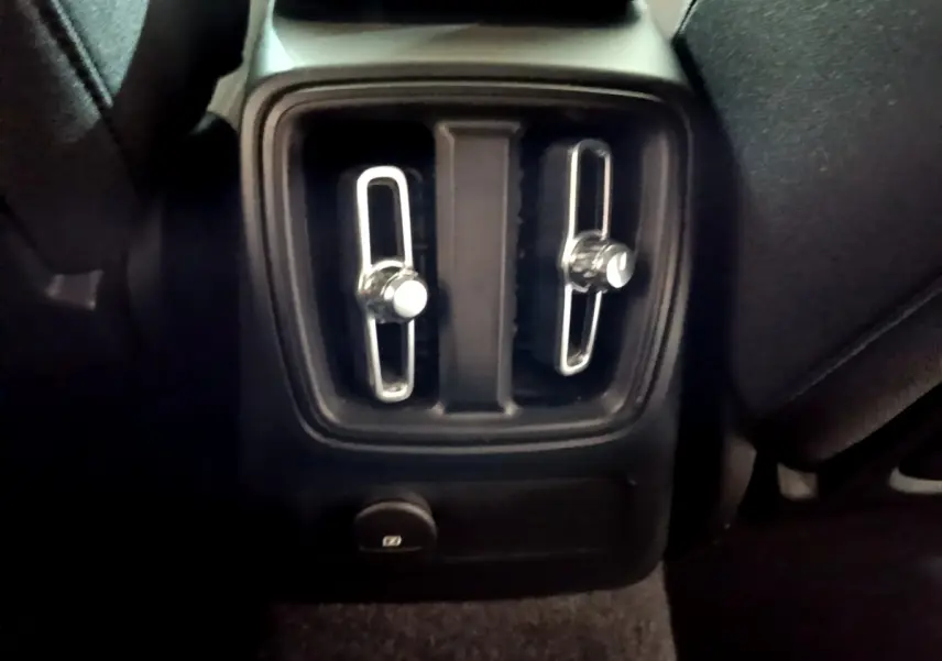 Gros plan sur les commandes d'aération arrière noires du Volvo XC40 Recharge T4 Business 2020, intérieur sombre.