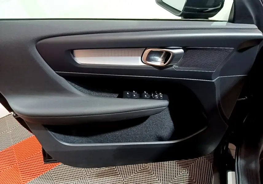 Gros plan sur la porte côté gauche du Volvo XC40 noir, avec poignée alu et commandes électriques des vitres.