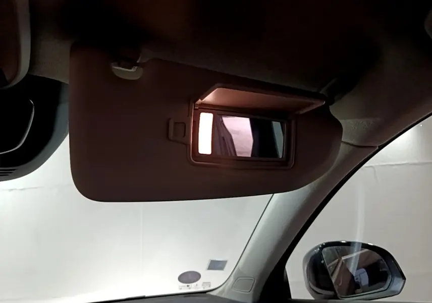 Miroir de courtoisie éclairé sur pare-soleil côté conducteur dans l'habitacle d'un Volvo XC40 noir.