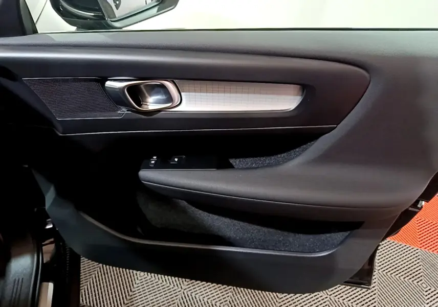 Détail de la porte côté conducteur du Volvo XC40 noir, avec poignée argentée et commandes de vitres intégrées.