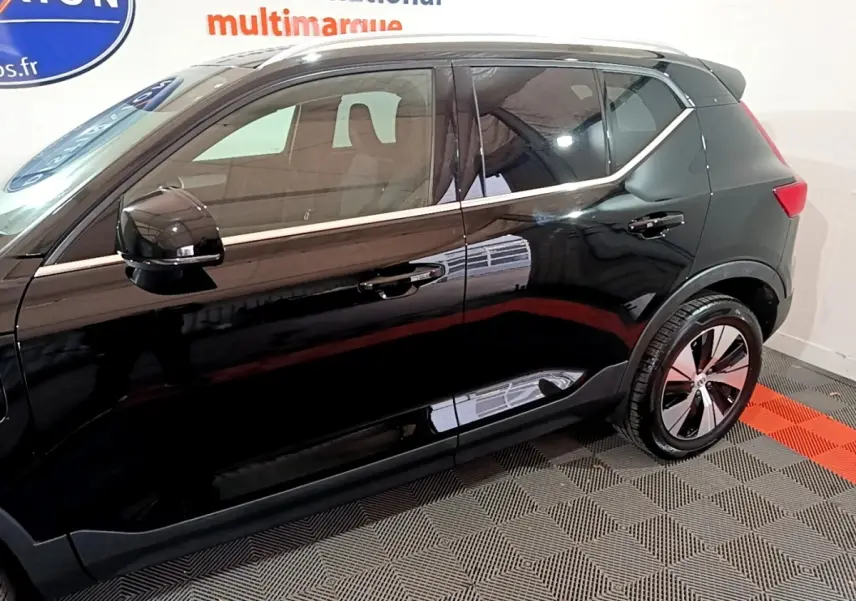 Vue latérale côté gauche du Volvo XC40 Recharge T4 Business noir, soulignant ses jantes modernes et la ligne chromée au-dessus des portières.