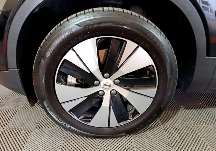 Gros plan sur la roue avant droite noire du Volvo XC40 Recharge T4 211 DCT7 Business avec jante bicolore moderne.