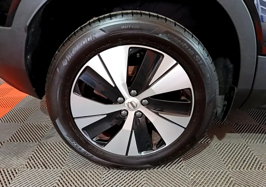 Gros plan sur la roue avant droite du Volvo XC40 noir, mettant en valeur la jante bicolore et le pneu Hankook.