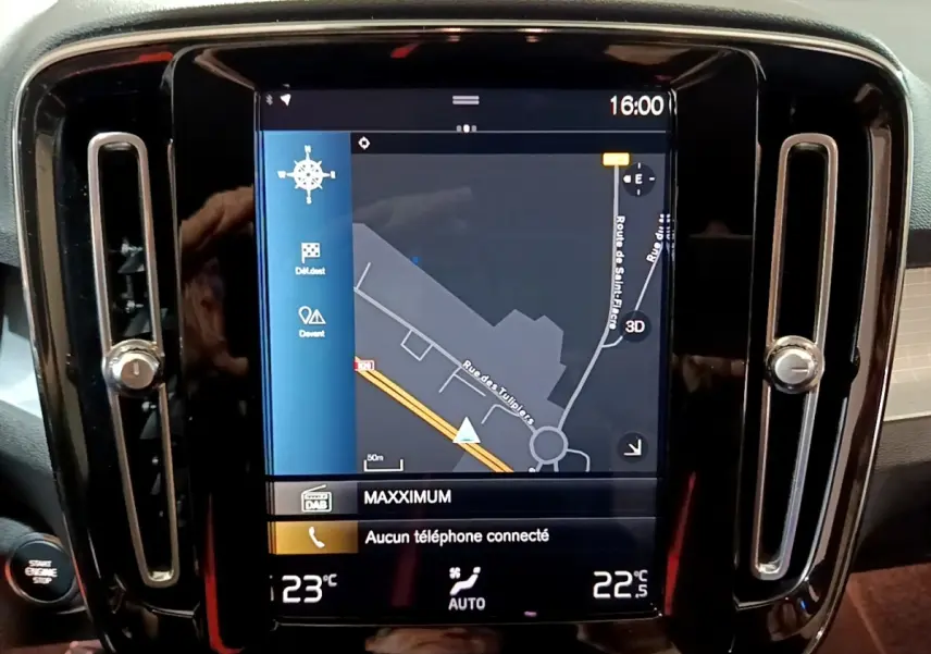 Écran tactile central affichant la navigation dans un Volvo XC40 noir, avec ventilation et bouton démarrage visibles.
