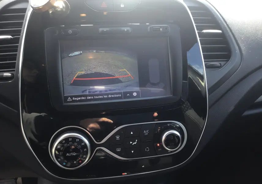 Vue rapprochée de la console centrale noire du Renault Captur beige/marron, avec écran de caméra de recul et commandes de climatisation.