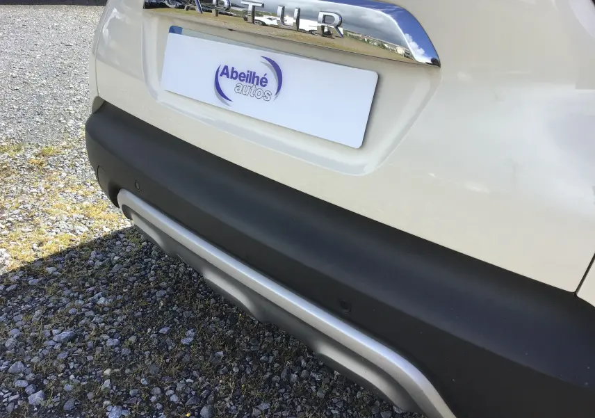 Gros plan sur la partie arrière beige du Renault Captur 2018, mettant en valeur le logo chromé et le pare-chocs noir avec insert argenté.