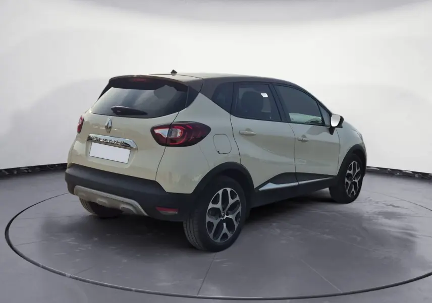 Vue 3/4 arrière droite d'un Renault Captur beige/marron 2018 avec toit noir et jantes alliage noires.