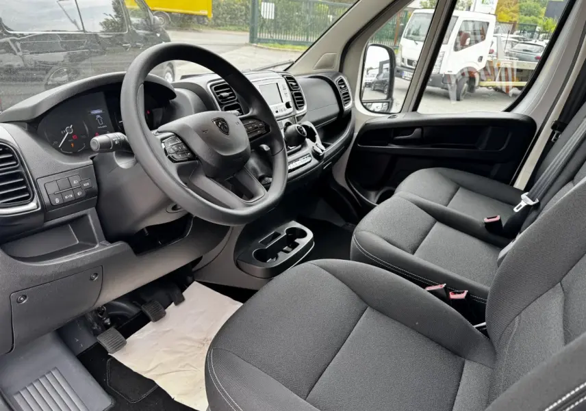Intérieur du Peugeot Boxer Fourgon L2H1 2026 vu côté conducteur, montrant tableau de bord et sièges gris foncé.