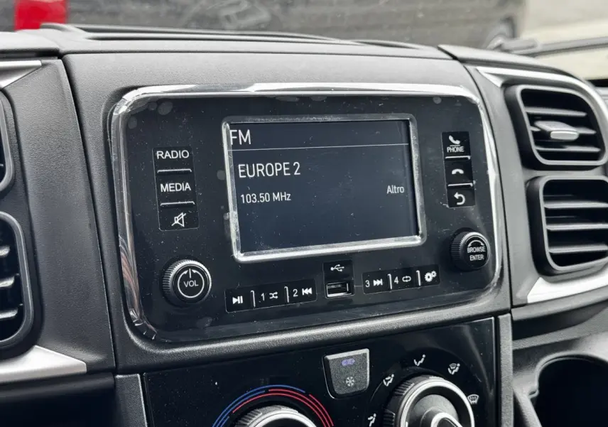 Gros plan sur l’écran multimédia et la console centrale noire du Peugeot Boxer Fourgon blanc, intérieur avant.
