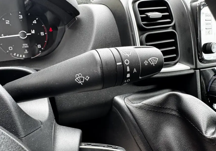 Gros plan sur la manette d’essuie-glace noire du tableau de bord du Peugeot Boxer Fourgon blanc, intérieur avant.