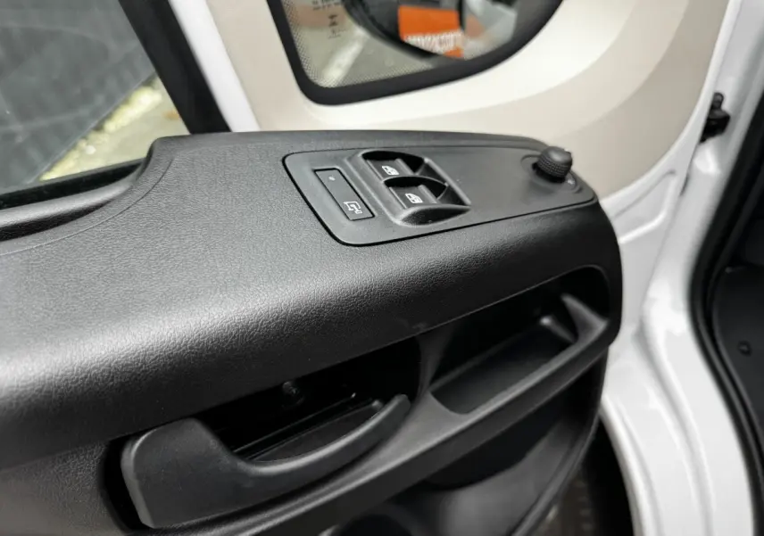 Détail de la porte avant gauche blanche du Peugeot Boxer Fourgon avec commandes électriques des vitres et rétroviseur.