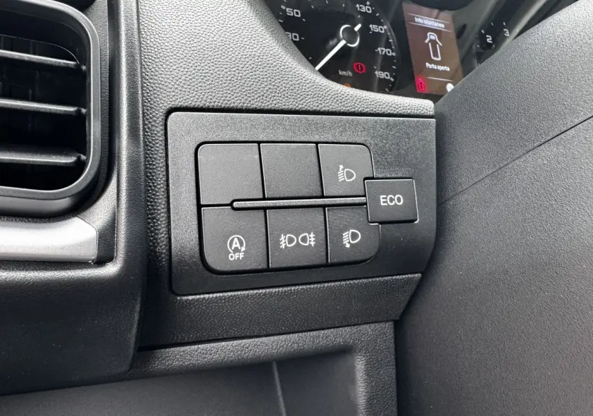 Gros plan sur les commandes d’éclairage et mode ECO du tableau de bord noir du Peugeot Boxer Fourgon blanc.