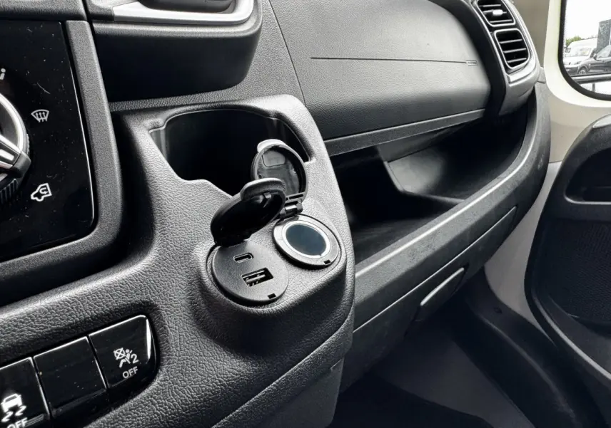 Détail intérieur côté passager du Peugeot Boxer Fourgon blanc 2026 montrant prise USB et port 12V ouverts sur tableau de bord.