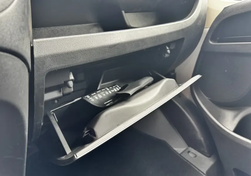Gant de boîte à gants ouvert côté passager dans un Peugeot Boxer Fourgon blanc, montrant un manuel et un rangement intérieur.