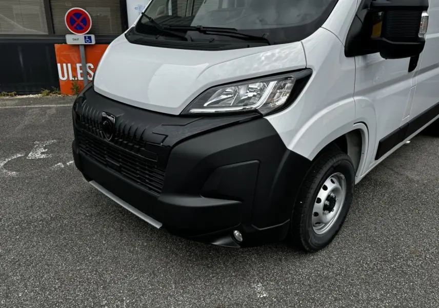 Vue 3/4 avant droit du Peugeot Boxer Fourgon blanc avec pare-chocs noir et phares modernes halogènes.