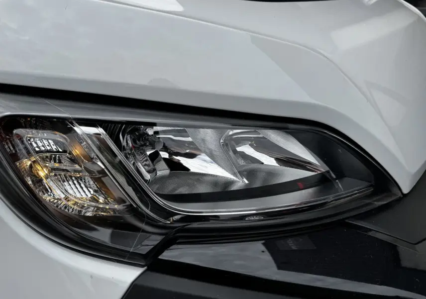 Gros plan sur le phare avant droit du Peugeot Boxer Fourgon blanc, mettant en valeur ses détails lumineux et contours noirs.