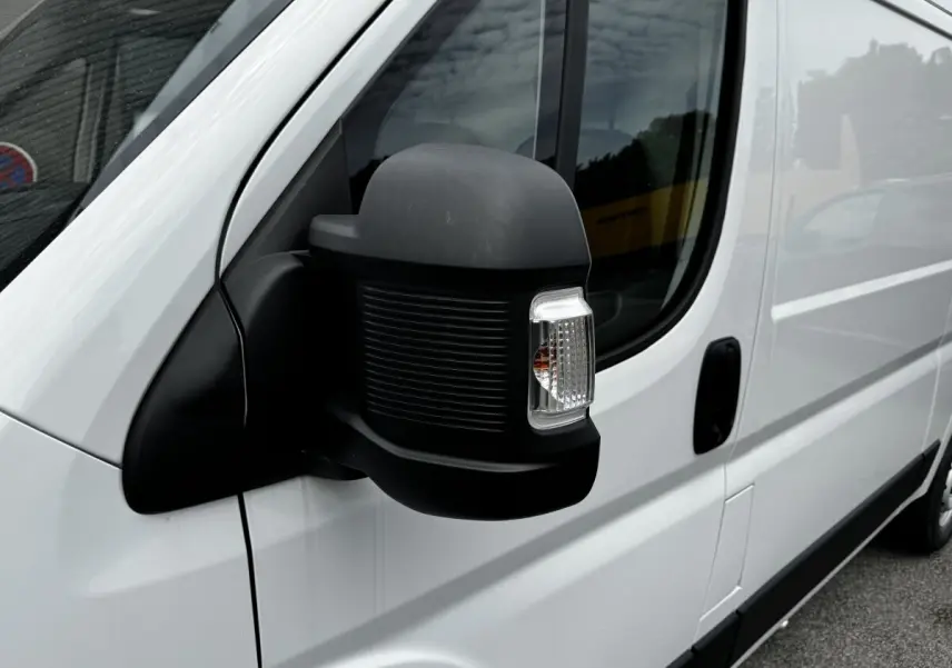 Gros plan sur le rétroviseur noir côté conducteur du Peugeot Boxer Fourgon blanc, vue latérale avant droite.