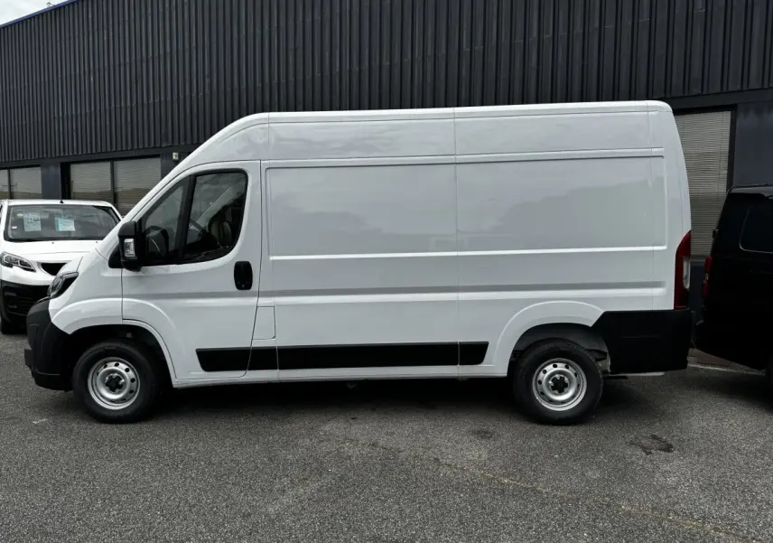 Vue de profil côté gauche d'un Peugeot Boxer Fourgon blanc, avec protections noires sur les bas de caisse et roues acier.