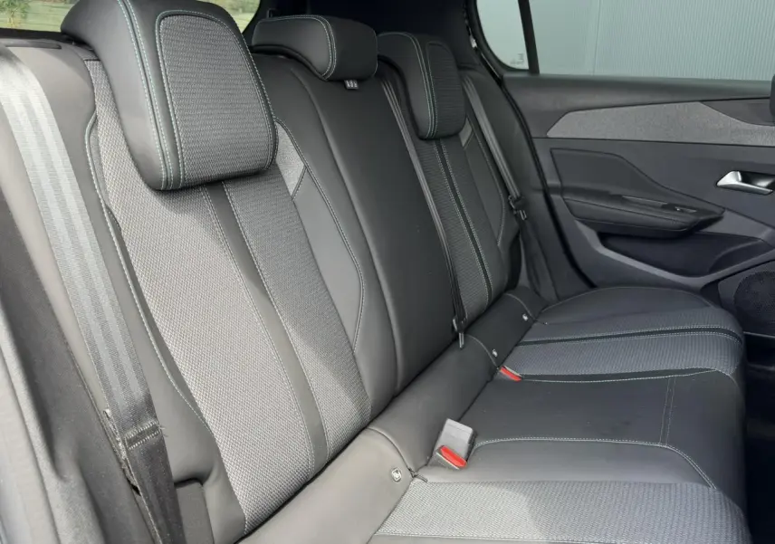 Vue intérieure côté droit des sièges arrière noirs avec surpiqûres bleues du Peugeot 308 Hybrid 145 e-DSC6 Allure 2025.