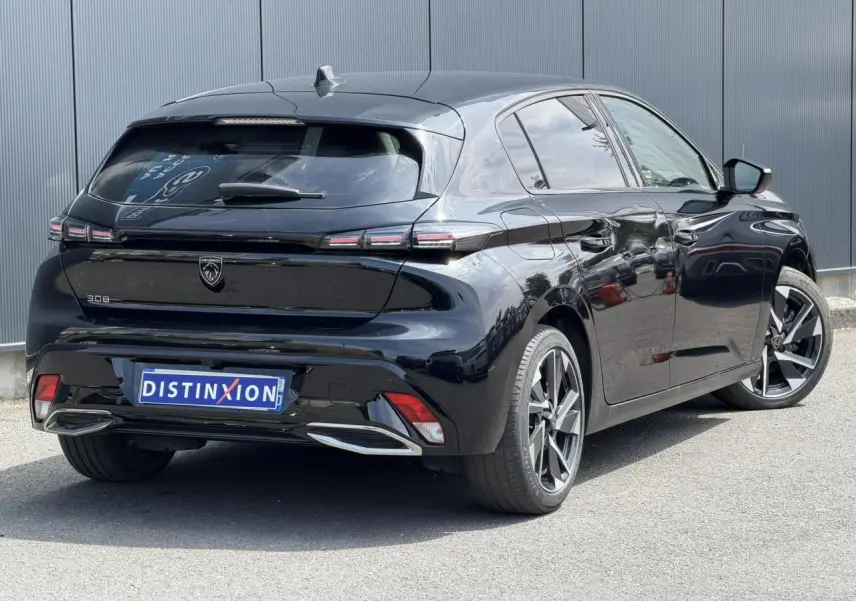 Vue 3/4 arrière droite d'une Peugeot 308 Hybrid 145 noire Perla avec jantes alliage 17 pouces et feux LED distinctifs.