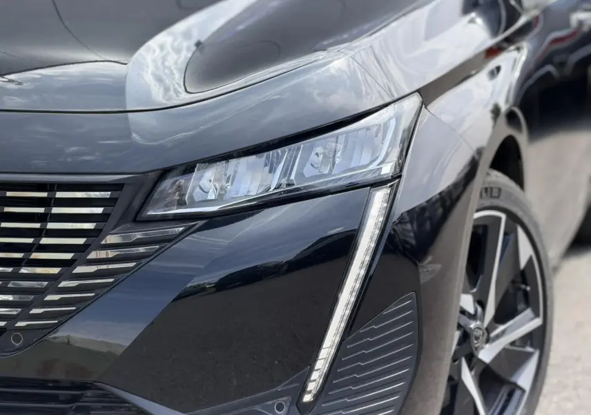 Gros plan sur l'avant droit noir Perla de la Peugeot 308 Hybrid 145 avec feux LED et jante alliage 17 pouces.
