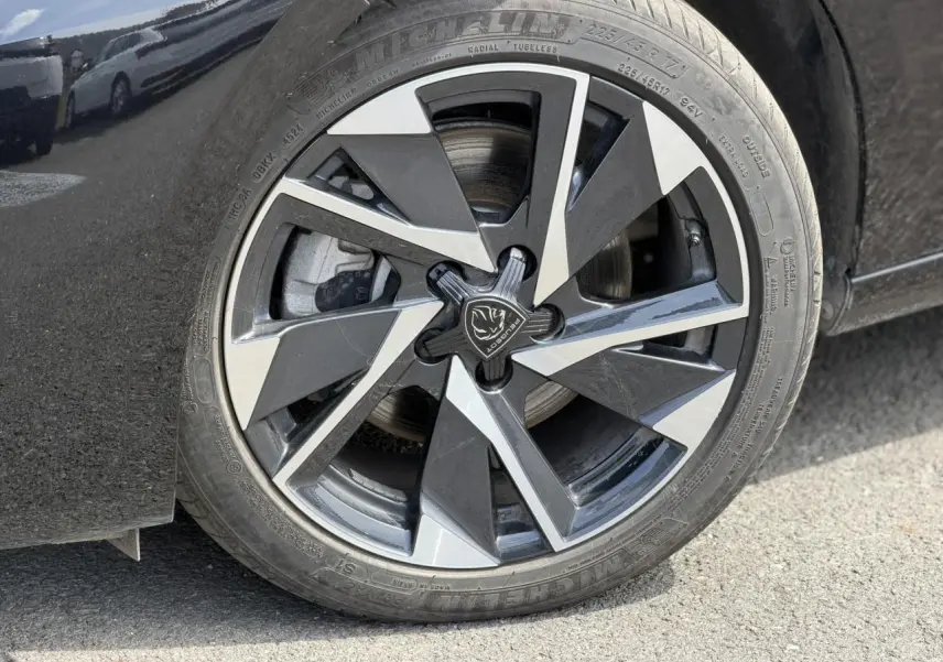 Gros plan sur la jante alliage 17'' Halong diamantée noire et argentée du côté gauche d'une Peugeot 308 Hybrid 2025 noir Perla.