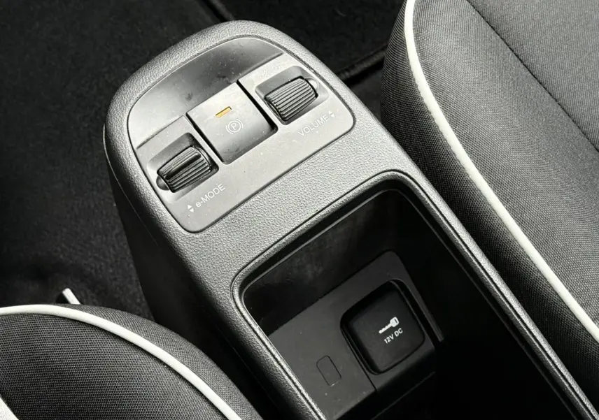 Gros plan sur la console centrale noire avec commandes e-Mode, frein électrique et prise 12V dans une Fiat 500 électrique 2024.