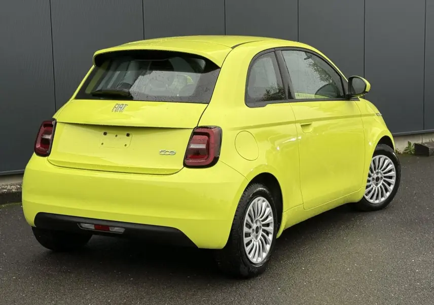 Vue 3/4 arrière droite d'une Fiat 500 électrique 2024 en jaune Acid, avec feux arrière LED et jantes argentées.