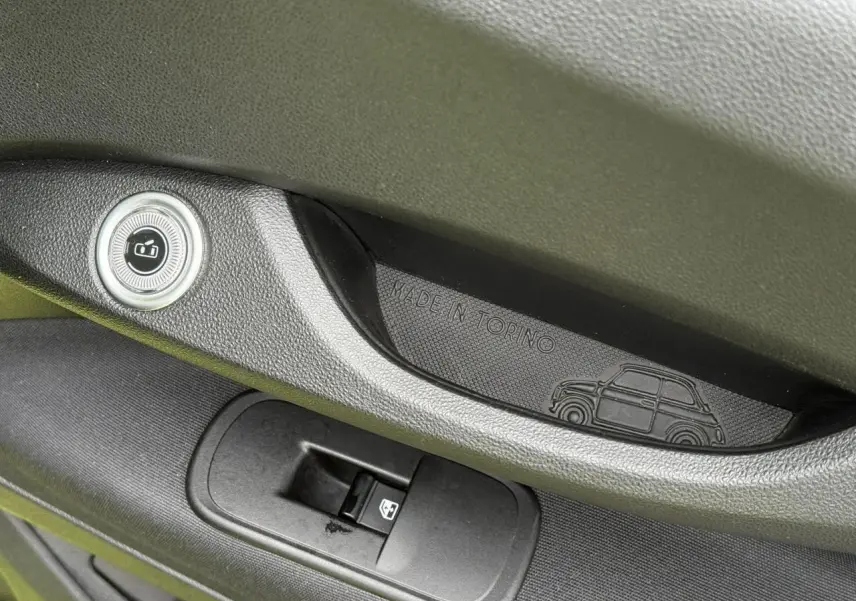 Gros plan sur la poignée intérieure côté gauche de la porte d’une FIAT 500 électrique avec gravure "Made in Torino" et silhouette de voiture.