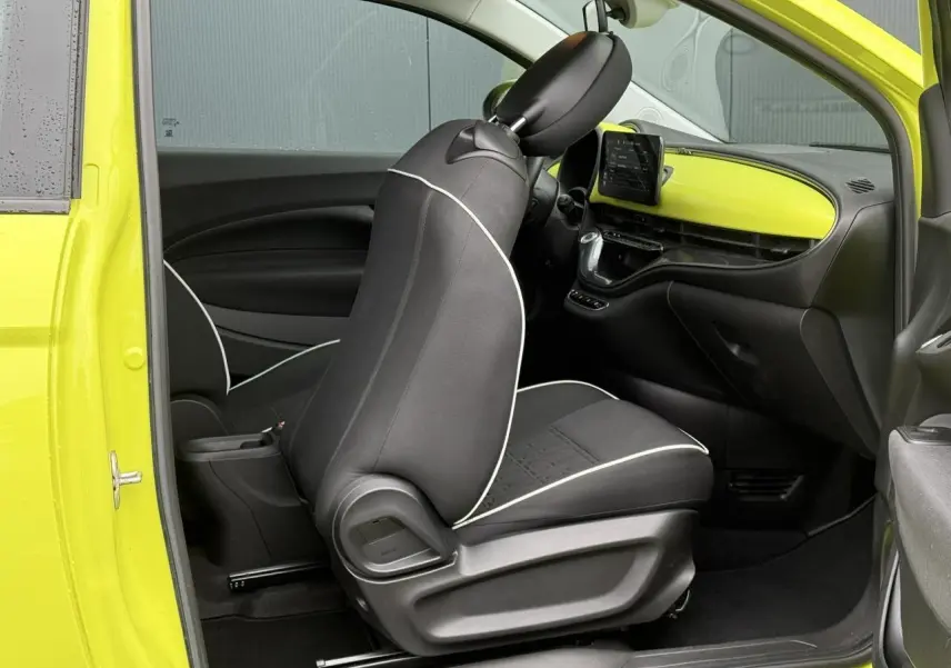 Vue intérieure côté conducteur d'une FIAT 500 électrique jaune Acid, avec sièges noirs et tableau de bord assorti.