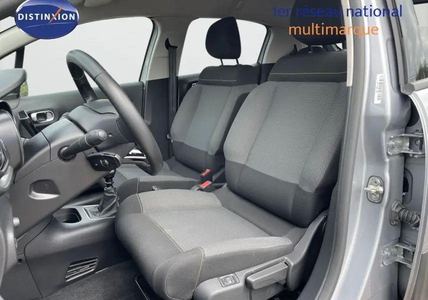 Vue intérieure côté conducteur de la Citroën C3 gris Artense 2021 avec sièges tissu gris et volant noir.