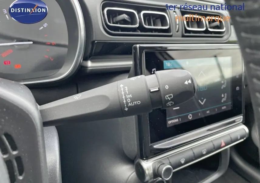 Gros plan sur la commande d'essuie-glace à gauche du volant dans l'habitacle gris noir d'une Citroën C3 2021.