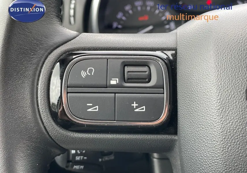 Gros plan sur les commandes au volant d'une Citroën C3 2021 gris Artense, mettant en valeur les boutons de réglage audio.