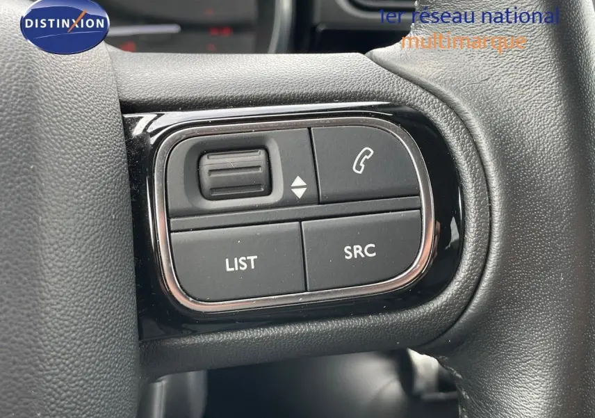 Gros plan sur les commandes du volant d'une Citroën C3 2021 gris Artense, boutons pour téléphone et audio visibles.