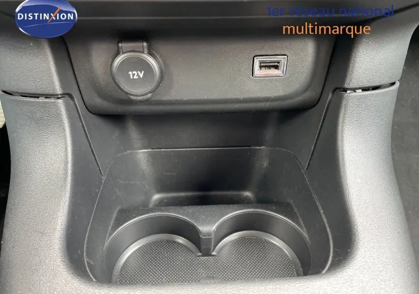 Gros plan sur la console centrale noire du Citroën C3 2021 montrant prise 12V et port USB au-dessus des porte-gobelets.