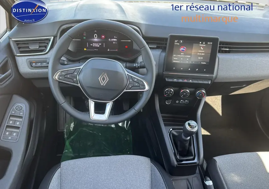 Vue intérieure centrée sur le volant cuir et la console centrale avec levier de vitesse manuelle de la Renault Clio V gris rafale.