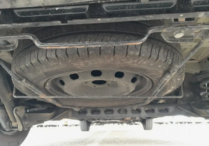 Vue en contre-plongée sous un Renault Trafic Combi gris foncé, montrant la roue de secours fixée sous le châssis.