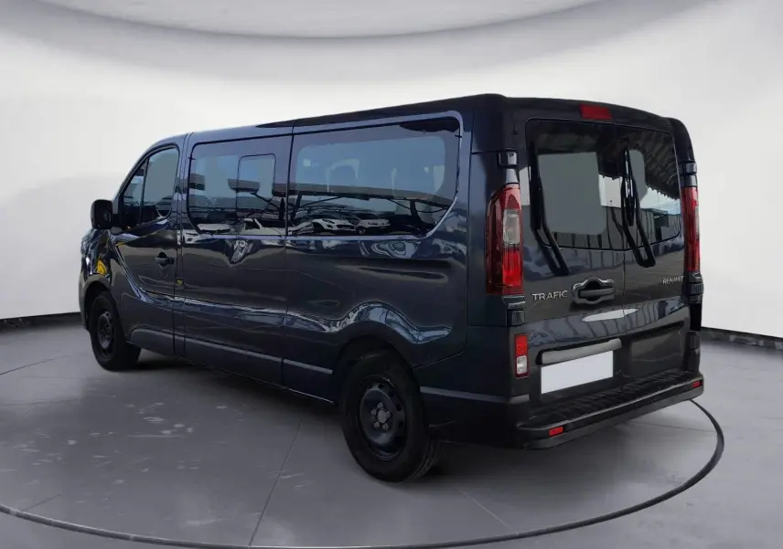 Vue 3/4 arrière droite du Renault Trafic Combi gris foncé métallisé, mettant en valeur ses grandes vitres latérales et ses feux arrière verticaux.