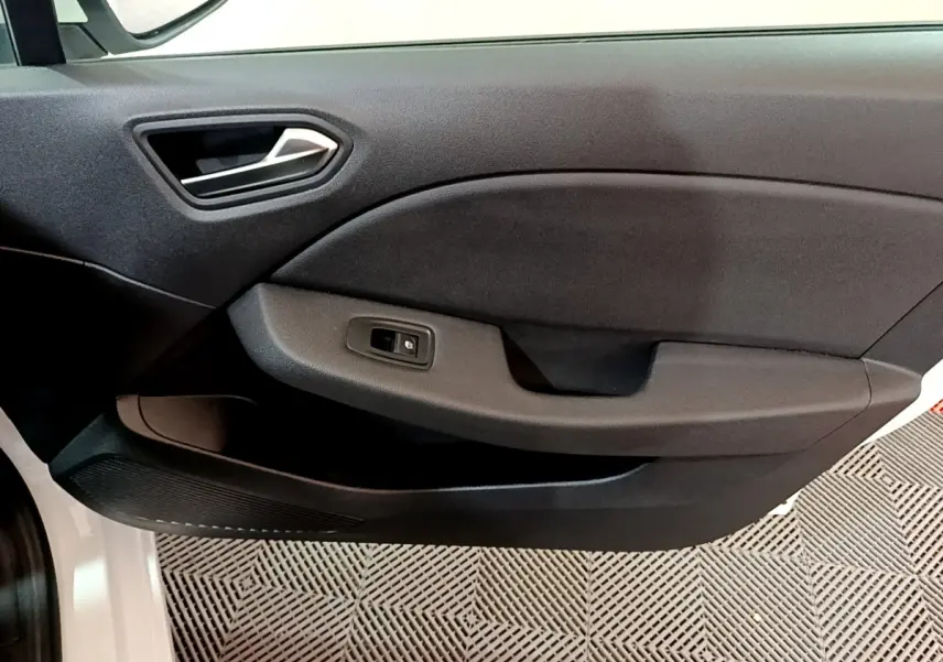 Gros plan sur la porte côté gauche intérieure noire de la Renault Clio Business blanche, avec poignée et bouton de vitre électrique visible.